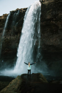 Girl in front a waterfall with her arms open 
